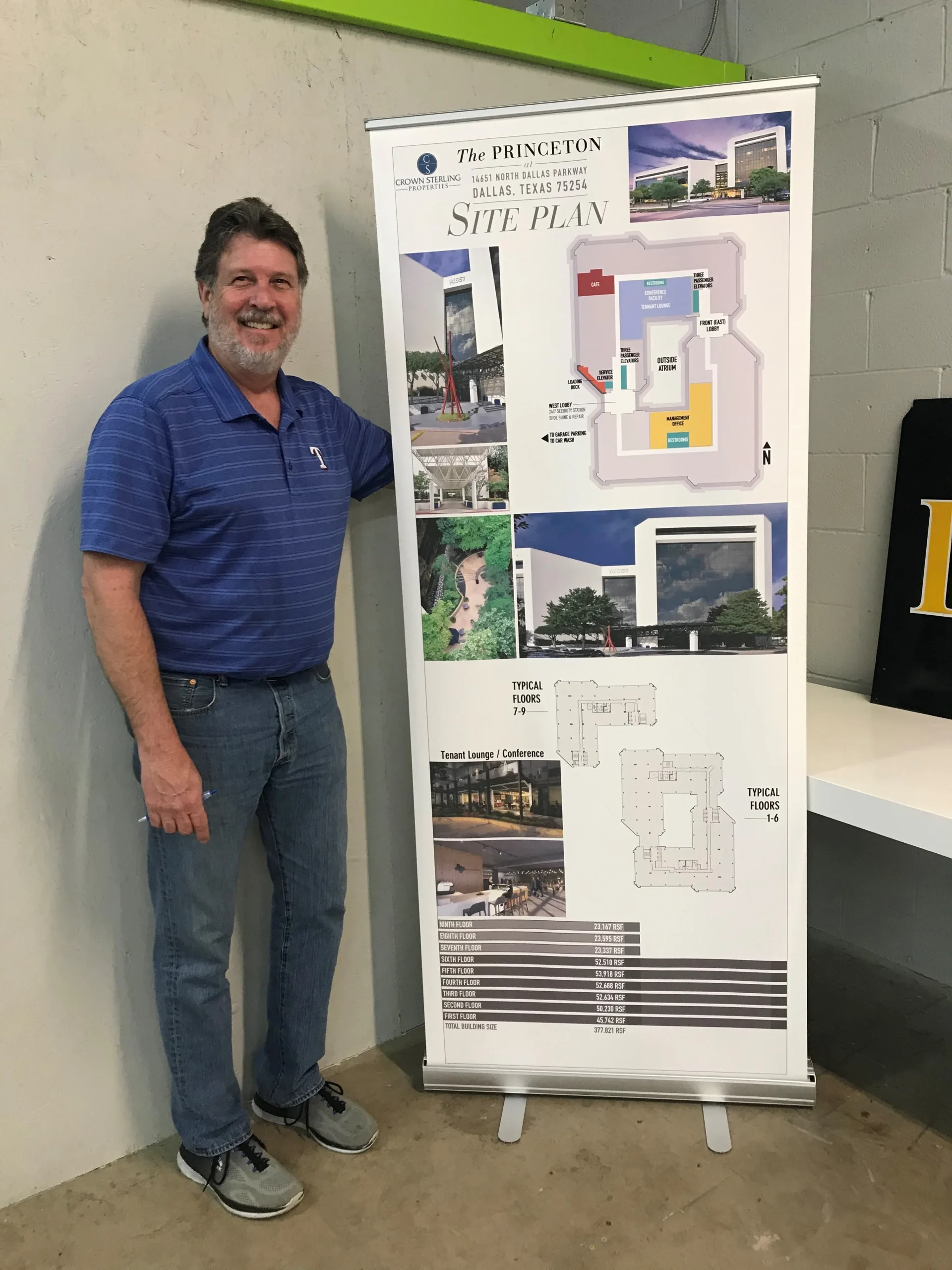 Image of a man smiling standing next to a large pull up banner.